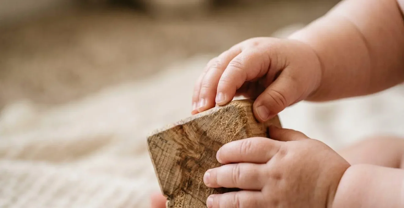 Extreme macro photograph of infant hands with developing pincer grasp exploring the varied textures of a simple wooden sensory block