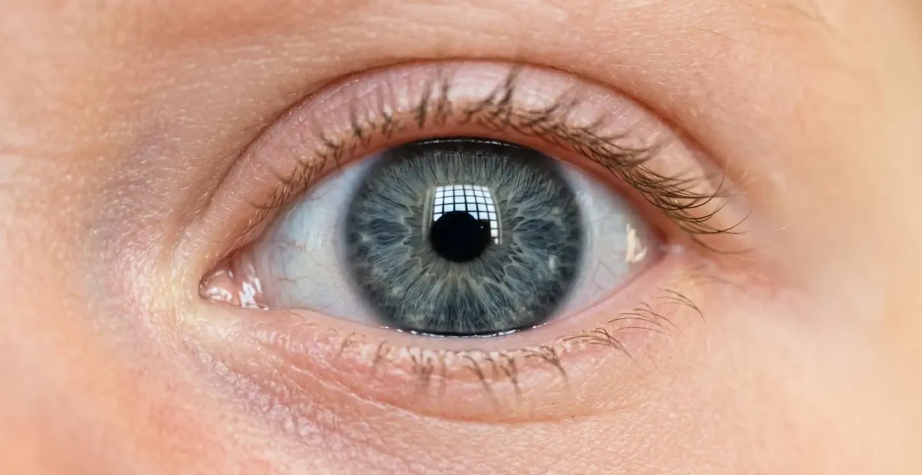 Macro photograph of a newborn's eye with high-contrast patterns reflected in the iris, showcasing early visual development