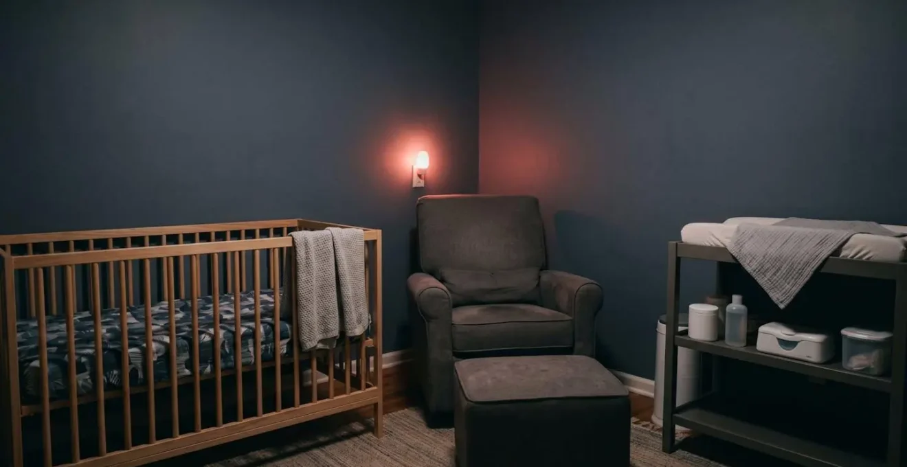 A minimalist nursery corner at night showing the spatial relationship between a crib, feeding chair, and changing station illuminated by soft red-toned lighting