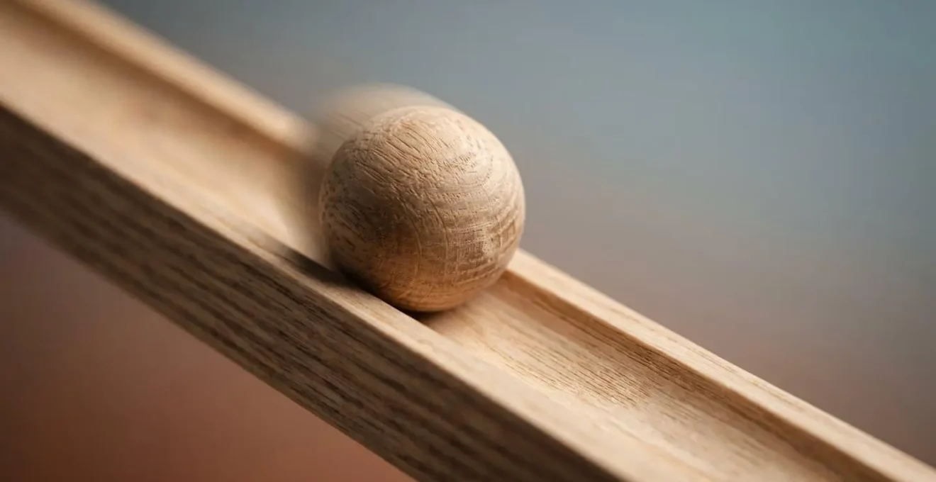 Macro photograph showing a wooden ball paused mid-roll on a simple ramp toy, capturing the textural details of natural wood grain and the precise moment of gravitational cause-and-effect